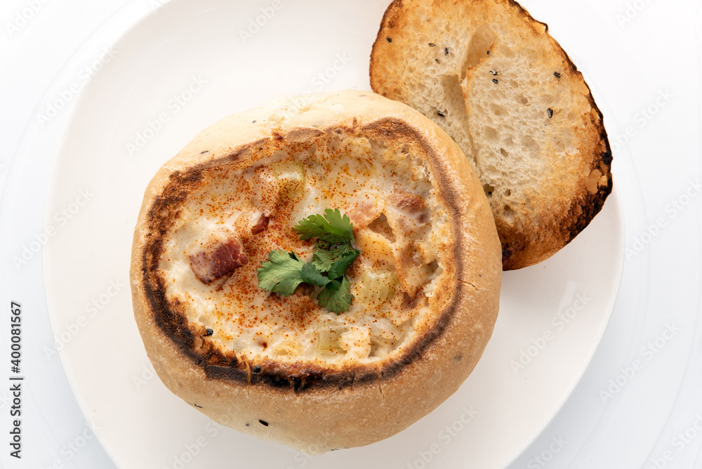 Overhead view of bowl of hearty clam chowder contained in an oven baked bread bowl.