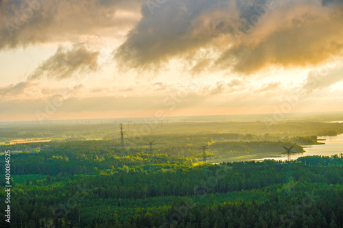 aerial view of green forests, lakes and a high-voltage transmission line under a cloudy sky