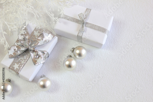 Bożonarodzeniowa srebrno-biała dekoracja z prezentami, bombkami i oszronionymi gałązkami 