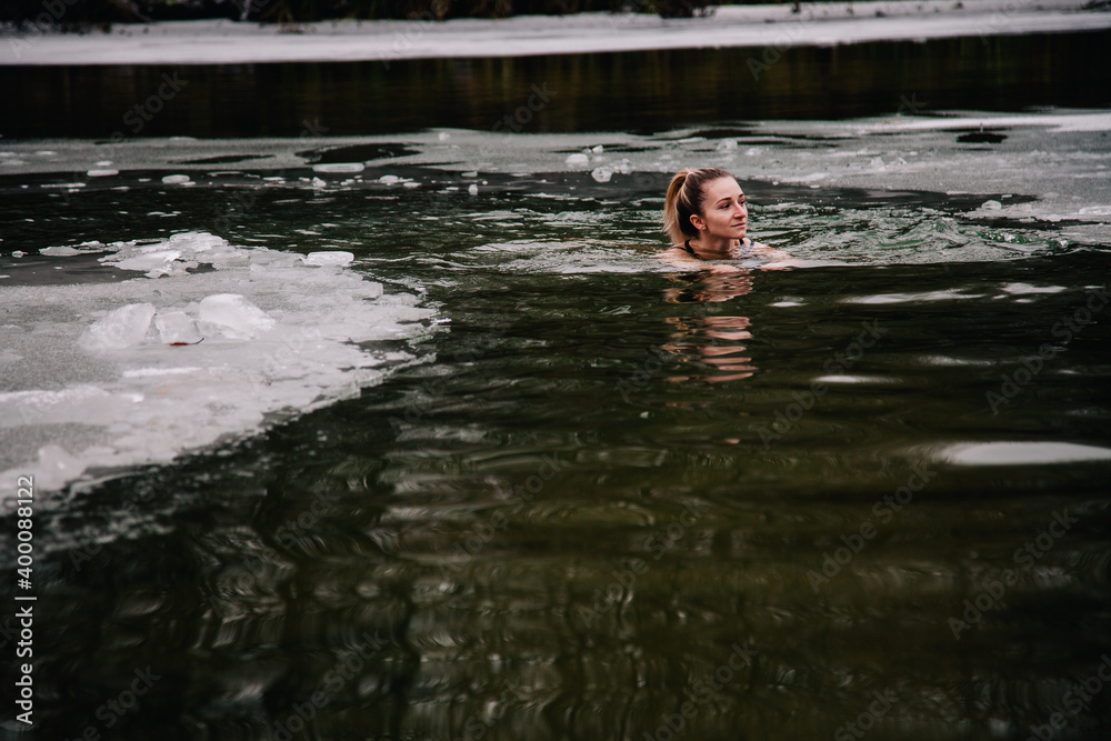 Fototapeta premium Young slender girl bathes in winter in a river hole