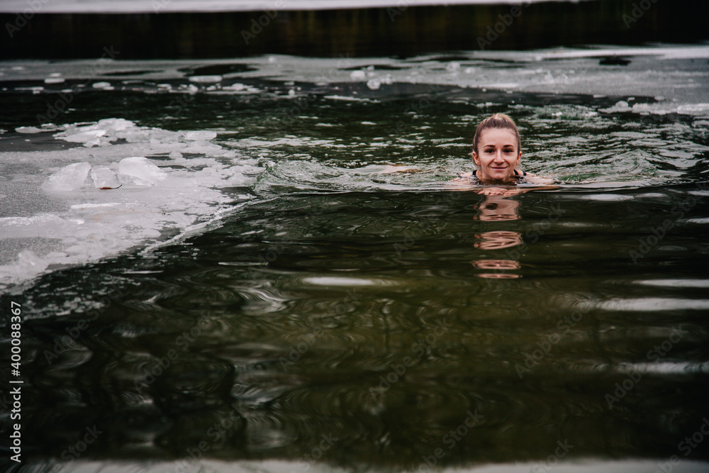 Fototapeta premium Young slender girl bathes in winter in a river hole