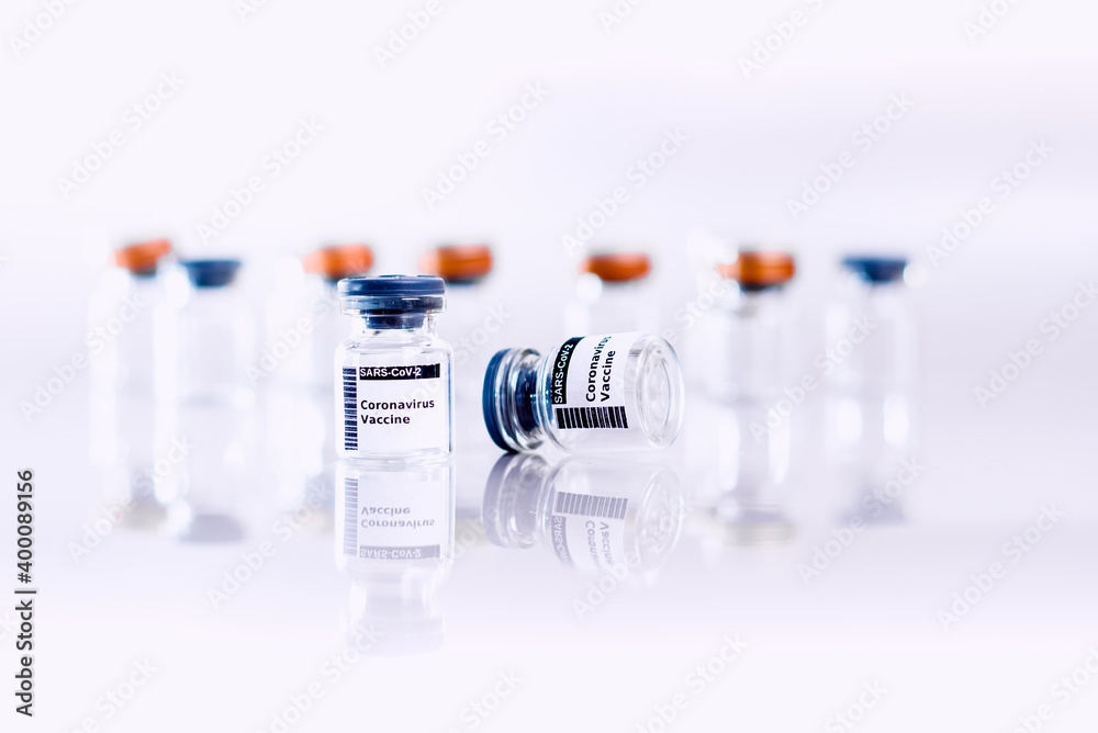 Two vials of vaccines against coronavirus (novel coronavirus disease, COVID-19, nCoV 2019) in the foreground along with many more out of focus on a white background. Two vials of vaccines against coronavirus (novel coronavirus disease, COVID-19, nCoV 2019) in the foreground along with many more out of focus on a white background.