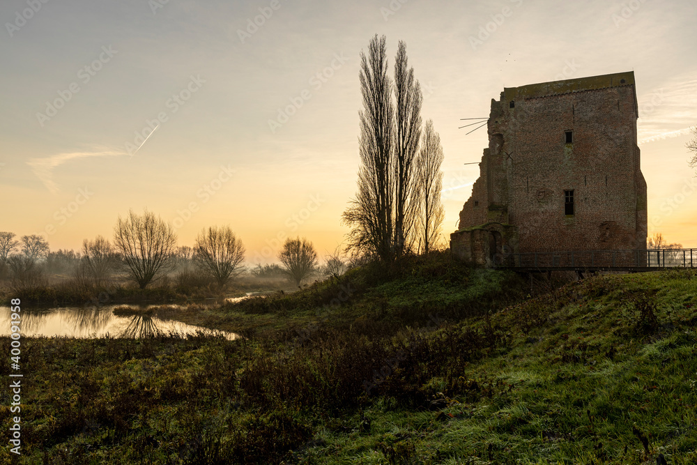 Silhouette of ruins of Nijenbeek castle in The Netherlands along the river IJssel in a swampland landscape at sunrise