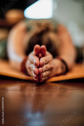 Woman lying down in child yoga position. Selective focus on hands.