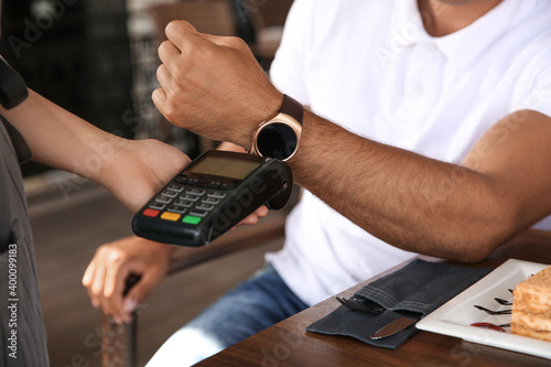Man making payment with smart watch in cafe, closeup © New Africa
