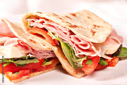 Traditional Italian piadina with ham, cheese, tomato and salad. photo
