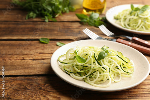 Tasty zucchini pasta with basil served on wooden table. Space for text
