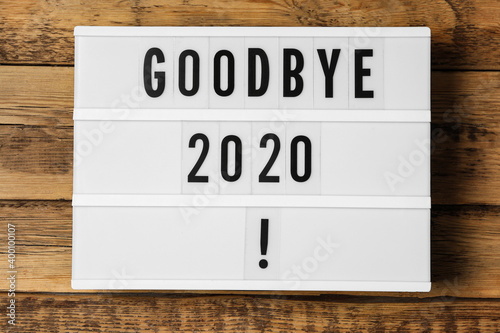 Fototapeta Naklejka Na Ścianę i Meble -  Lightbox with phrase Goodbye 2020! on wooden table, top view