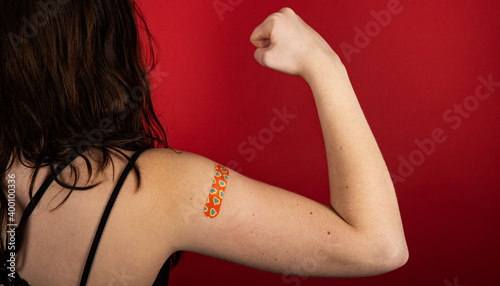 Female arm flexing bicep and making a fist wearing a bandage after receiving a Covid-19 Coronavirus vaccine injection photo