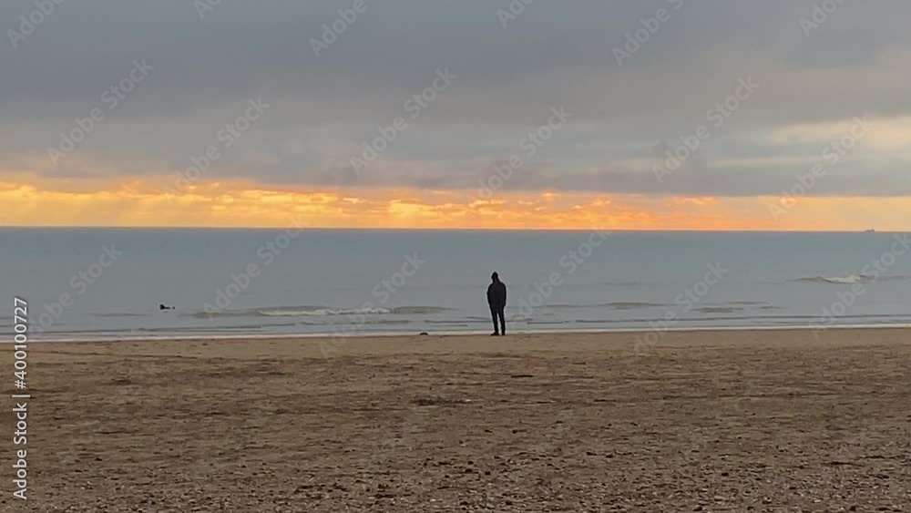 beach with man walking dog at sunset, Camber sands beach popular in summer with day trippers and winter with horse riders and dog walkers beach with man walking dog at sunset, Camber sands beach popular in summer with day trippers and winter with horse riders and dog walkers