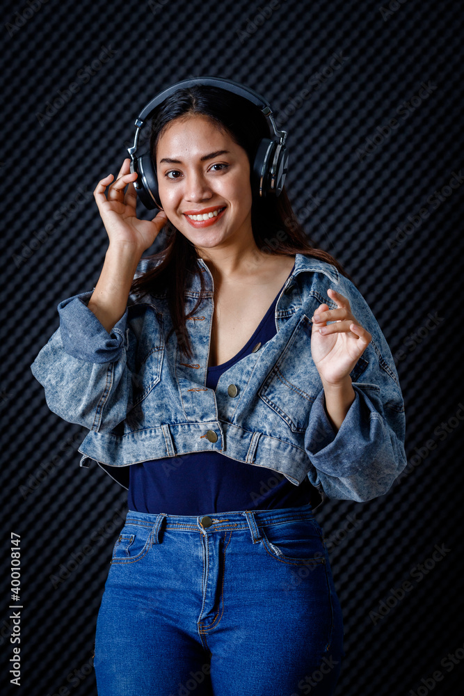 Happy cheerful pretty smiling of portrait of young Asian woman vocalist Wearing Headphones recording a song in a professional studio Happy cheerful pretty smiling of portrait of young Asian woman vocalist Wearing Headphones recording a song in a professional studio