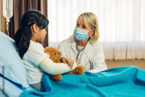 Woman doctor service help support discussing and consulting talk to little girl patient give teddy bear and check up information in hospital