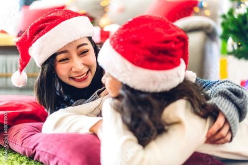 Portrait of happy asian family mother with daughter in santa hats having fun look at camera and enjoying spending time together in christmas time at home