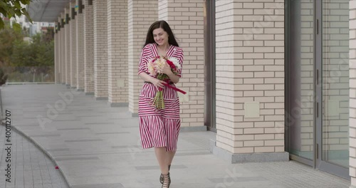 game in a chic striped dress happy goes after a date with a bouquet of flowers