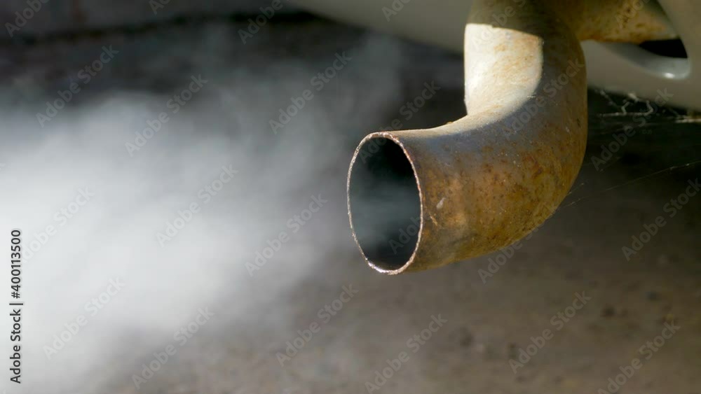 Closeup POV shot of fumes / smoke belching from the rear exhaust tail pipe of an old classic / vintage  car, just after being started, with water in the pipe due to the cold. Stock Video | Adobe Stock