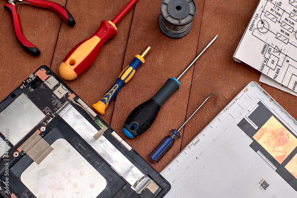 PC-tablet disassembled into parts. Screwdrivers. Electronics repair shops. workplace. Round pliers. Coil with tin. Scheme.