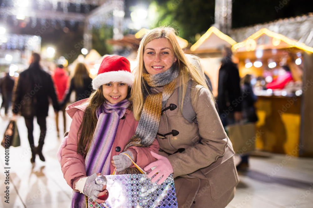 Joyous mother with little daughter buying decorations for Xmas at an open air market