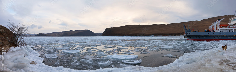  Baikal Lake on cold December morning. Panoramic view of the freezing Strait of Olkhon Gate and passenger ferry on shore. Beautiful winter landscape. Natural background. Winter travel and adventure