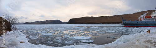  Baikal Lake on cold December morning. Panoramic view of the freezing Strait of Olkhon Gate and passenger ferry on shore. Beautiful winter landscape. Natural background. Winter travel and adventure