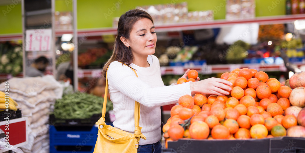 Smiling female customer picking fresh tomatoes in shop