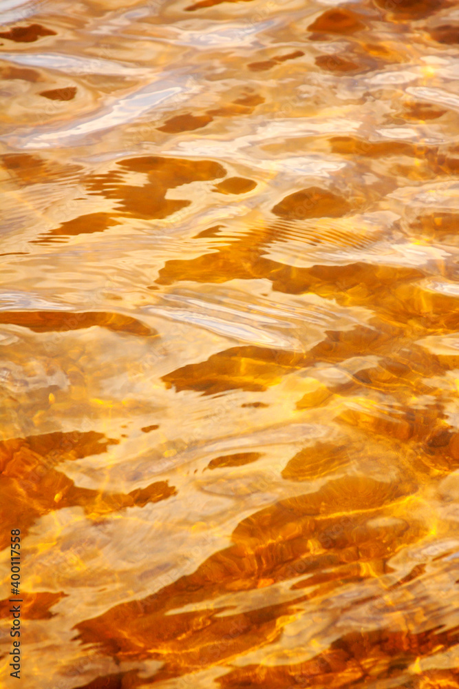 Yellow sandy bottom shines through clear wavy water