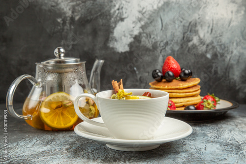 front view cup of tea with pancakes and fruits on a dark background morning breakfast food