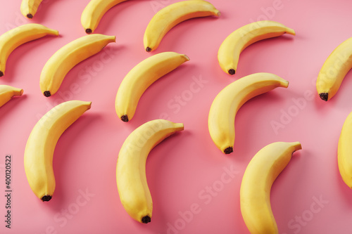 Yellow bananas scattered on pink background with texture pattern