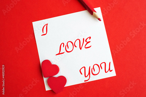 I love you written on a white sheet that lies on a red background. A declaration of love. Wedding and Valentine's Day