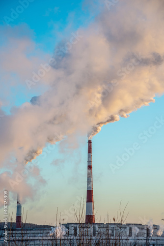 Powerful industrial factory chimney is smoking and polluting the environment with carbon dioxide