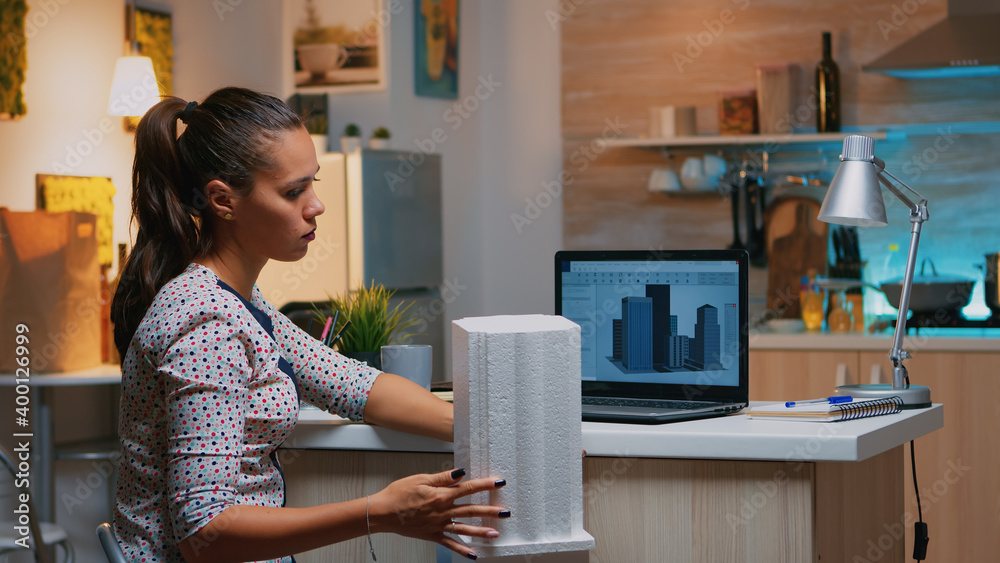 Freelancer architect working in 3D software to elaborate buildings design sitting at kitchen desk at night. Engineer artist creating and studying in office holding scale model, determination, career. Freelancer architect working in 3D software to elaborate buildings design sitting at kitchen desk at night. Engineer artist creating and studying in office holding scale model, determination, career.