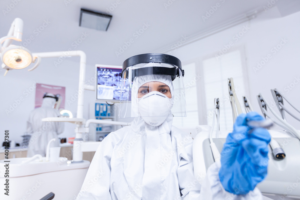 Patient pov of dentist taking precautions for covid virus examining tooth hygine. Stomatolog wearing safety gear against coronavirus during heatlhcare check of patient.