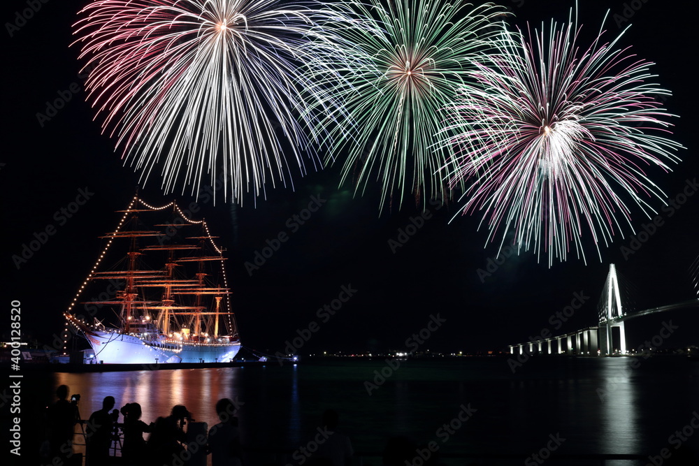 Naklejka premium 船が停泊する海上に打ちあがる夏の夜空の花火