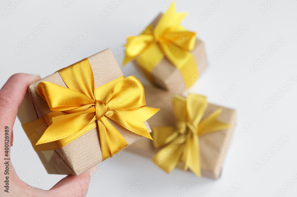 Tree gift boxes wrapped by kraft brown paper with beautiful yellow satin ribbons on ultimate gray background. Universal gifts design for all kind of celebration Tree gift boxes wrapped by kraft brown paper with beautiful yellow satin ribbons on ultimate gray background. Universal gifts design for all kind of celebration