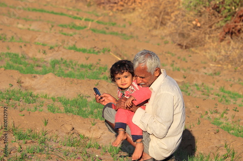 An Indian farmer grandfather and grandson following the crop in the field