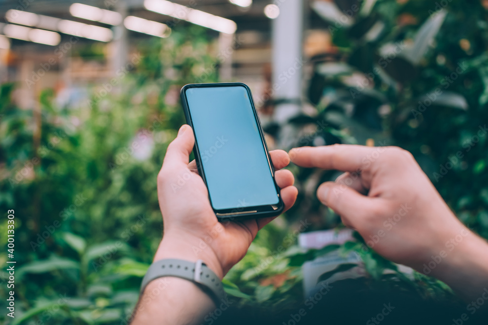 Mock-up technology. The guy holds a smartphone in his hands on the background flowers.