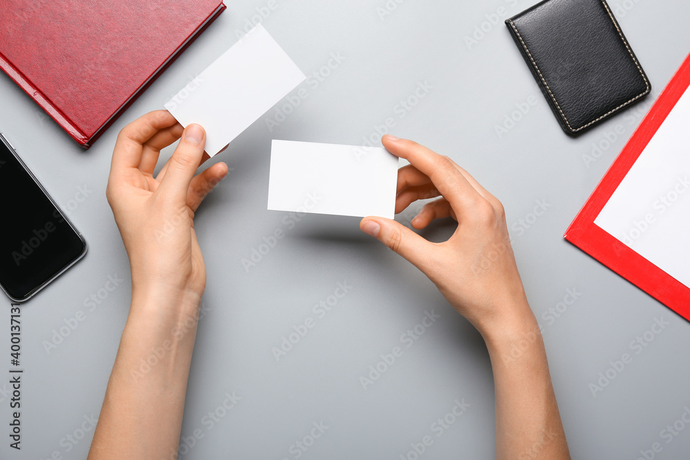 Hands with blank paper cards, mobile phone and stationery on gray background Hands with blank paper cards, mobile phone and stationery on gray background