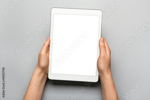Hands with tablet computer on gray background