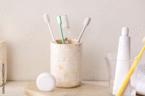 Holder with toothbrushes and toothpaste on table in bathroom