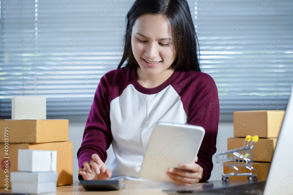 Female seller is checking the number of orders for her products that have been ordered using the tablet. Online Shopping and E-commerce concept. Female seller is checking the number of orders for her products that have been ordered using the tablet. Online Shopping and E-commerce concept.