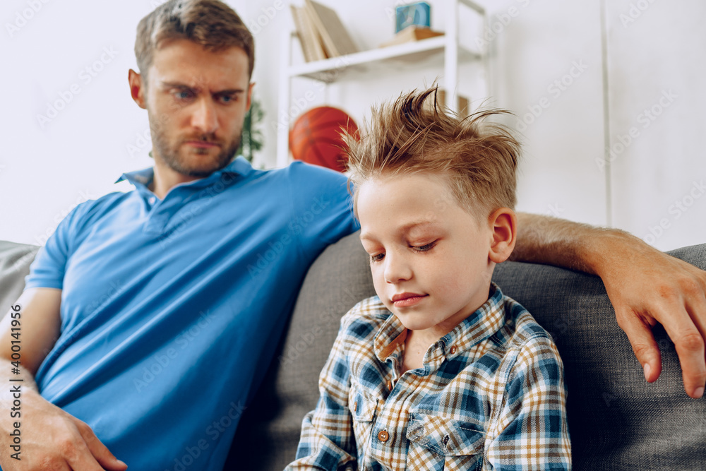 Obraz premium Father is having a talk with his little son while sitting on couch at home