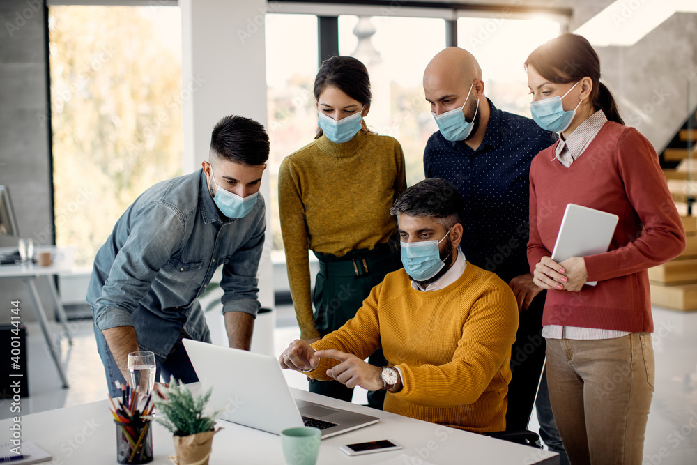 Business team wearing face masks while working on a computer in the office. Business team wearing face masks while working on a computer in the office.