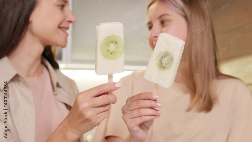 Close up of smiling mom and daughter holding sticks with fresh homemade ice-cream with kiwi slices enjoying summertime Close up of smiling mom and daughter holding sticks with fresh homemade ice-cream with kiwi slices enjoying summertime
