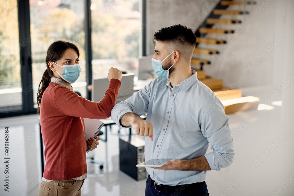 Fototapeta premium Two coworkers greeting with elbows in the office due to COVID-19 pandemic.