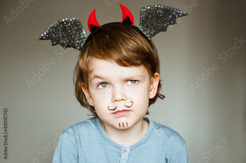 Portrait of an emotional child in a suit and face painting.