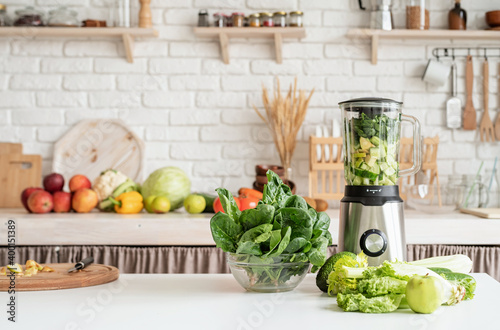 Home kitchen with a table with green vegetables and blender