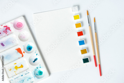 Watercolor paints and brushes on a white background. Mockup for artists. Layout for designers