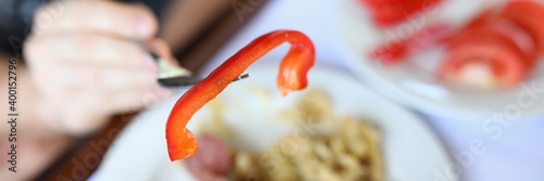 On background of dishes grilled sausages with garnish on fork closeup of red pepper. Healthy spicy food and how harmful it is concept
