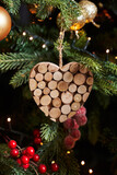 Christmas toy in the form of a heart which consists of round pieces of wood, golden balls hang in the background