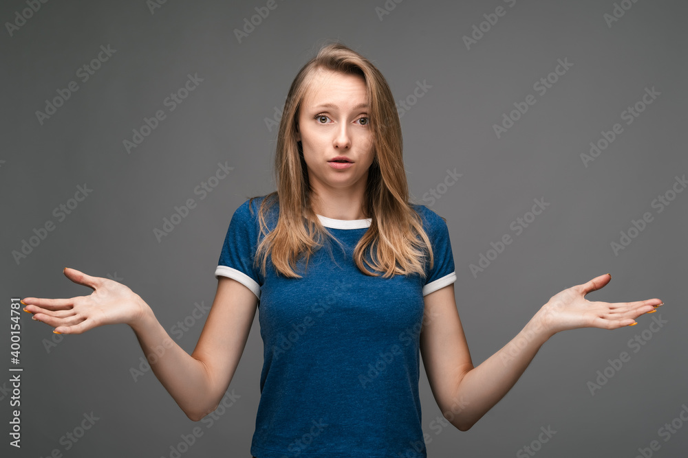 Studio shot of a clueless young woman shrugging shoulders. Concept of doubt, uncertainty and confusion Studio shot of a clueless young woman shrugging shoulders. Concept of doubt, uncertainty and confusion