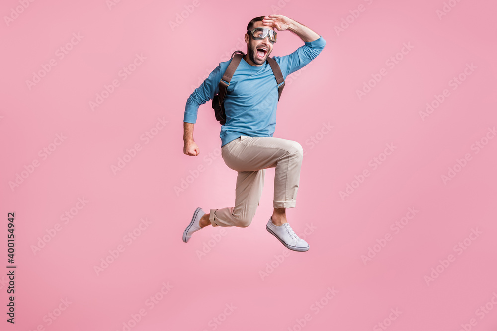 Full length photo of cute guy wear pullover glasses backpack skydive arm head looking far away isolated pink color background